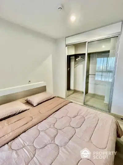 Modern bedroom with cozy bedding and mirrored wardrobe in a bright apartment.