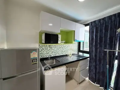 Modern kitchen with sleek cabinets, mosaic backsplash, and large window for natural light.