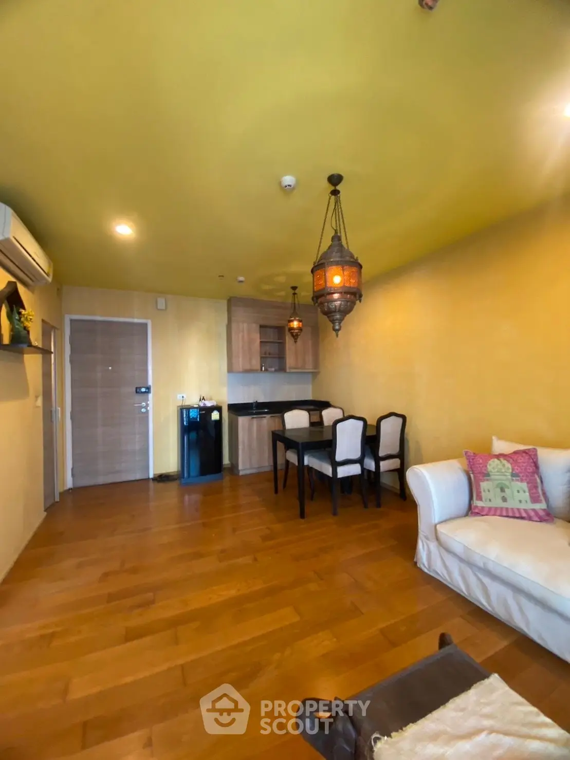 Charming living room with warm wooden flooring and elegant dining area, featuring cozy seating and ambient lighting.