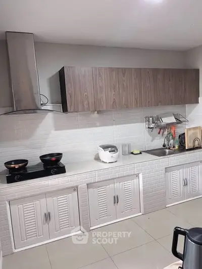 Modern kitchen with sleek cabinetry and dual-burner stove, perfect for culinary enthusiasts.