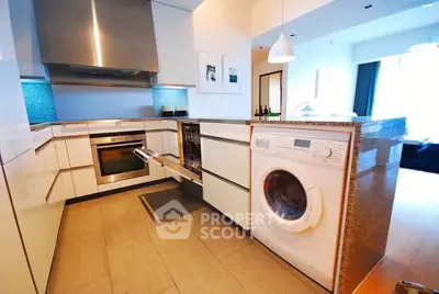Modern kitchen with sleek appliances including oven and washing machine, open layout design.