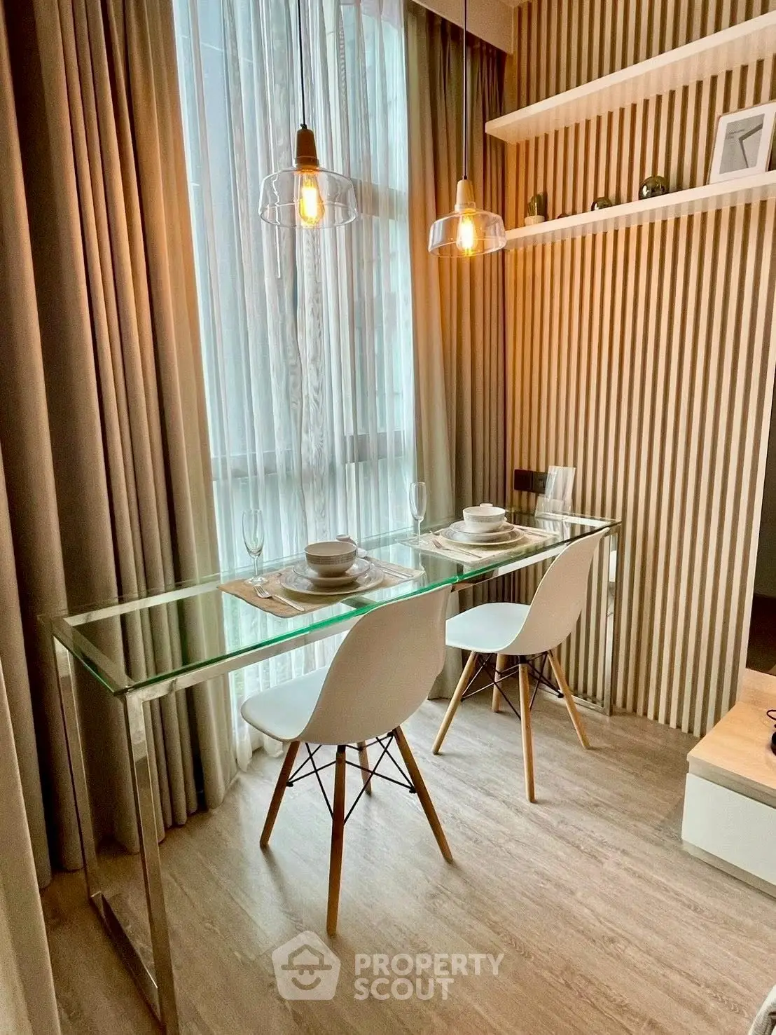 Modern dining area with glass table and stylish chairs in a cozy apartment setting.