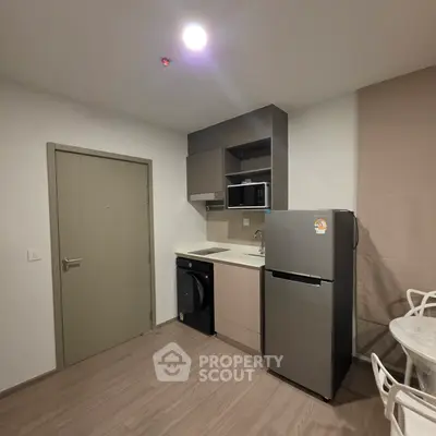 Modern compact kitchen with sleek appliances and dining area in a stylish apartment.