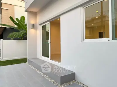 Modern minimalist exterior with sliding glass door and sleek patio design.