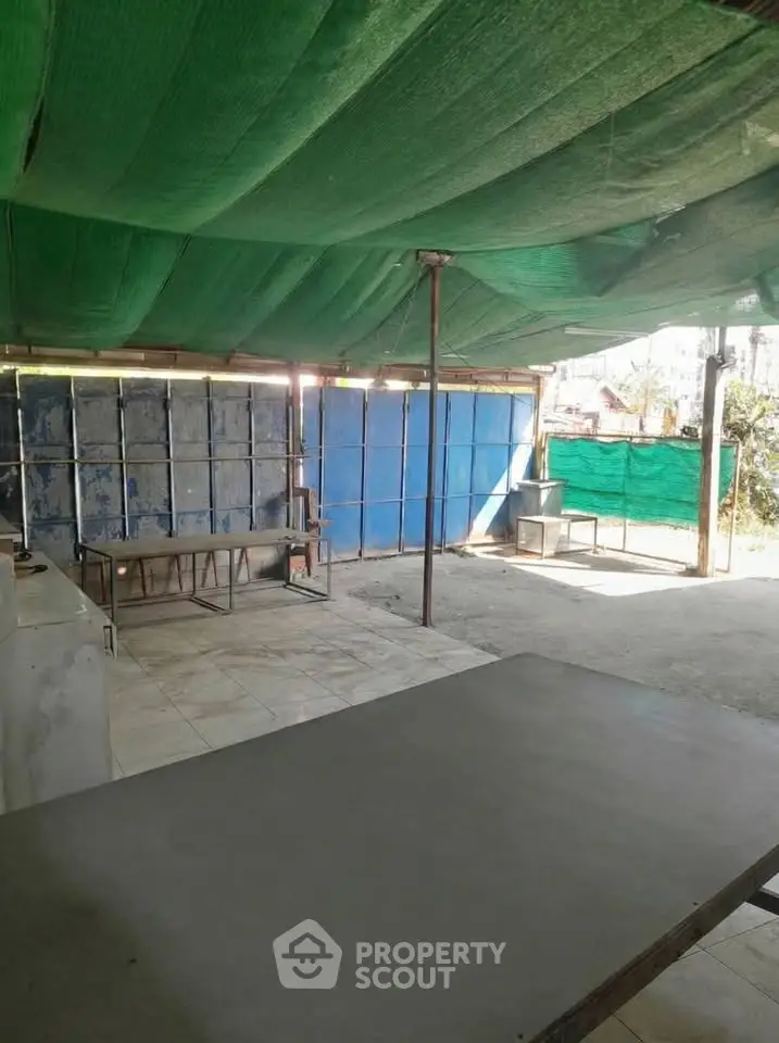 Spacious outdoor area with covered roof and tiled flooring, ideal for versatile use.