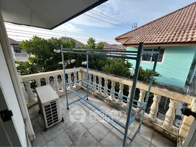 Charming balcony with lush greenery and tiled flooring, perfect for relaxation.
