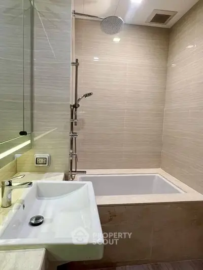 Modern bathroom with sleek sink and luxurious bathtub in elegant beige tones.
