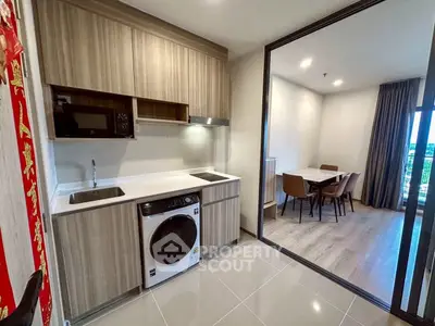 Modern kitchen with washing machine and dining area, sleek cabinetry and open layout.