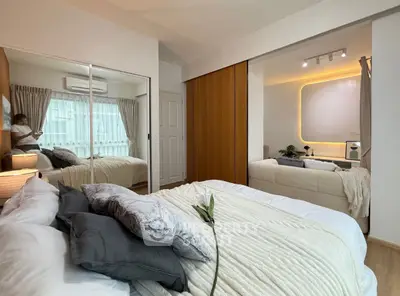 Modern bedroom with cozy bedding and mirrored wardrobe in stylish apartment.