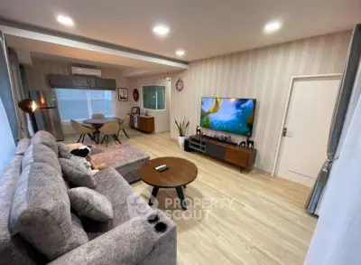 Spacious modern living room with stylish decor and large TV, perfect for relaxation and entertainment.