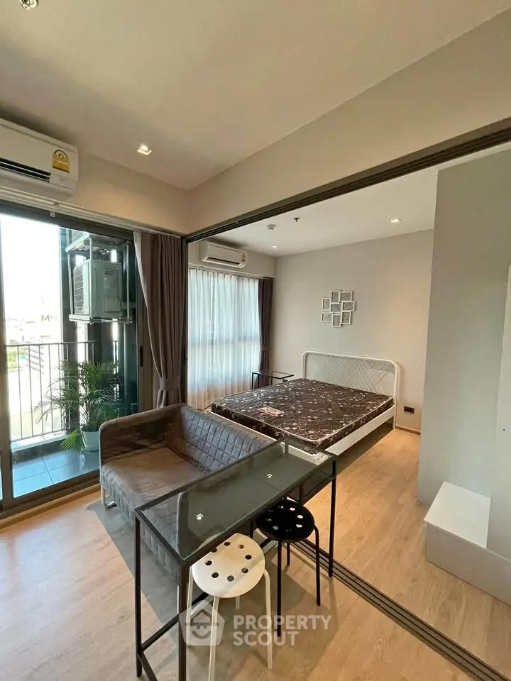 Modern studio apartment with balcony, featuring a cozy bed and stylish seating area.