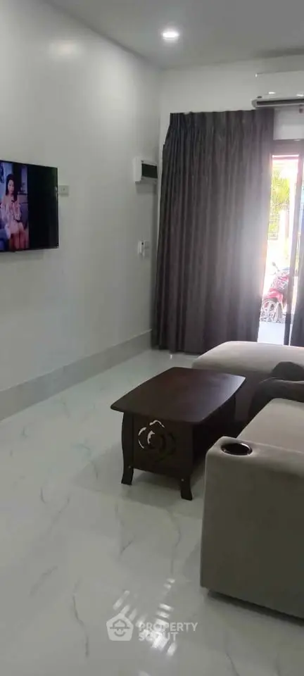 Modern living room with sleek furniture and wall-mounted TV, perfect for relaxation.