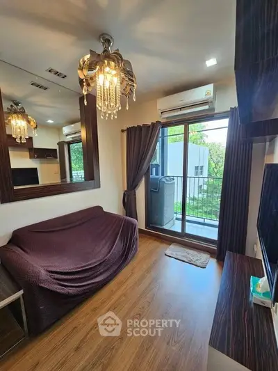 Chic living room with elegant chandelier and balcony view, perfect for modern urban living.