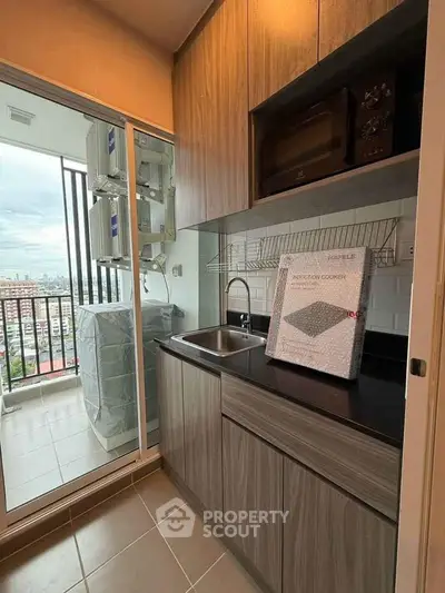 Modern kitchen with sleek cabinetry and balcony view in urban apartment.