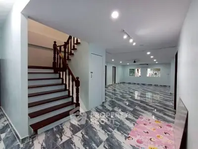 Spacious open-plan living area with elegant staircase and modern tiled flooring