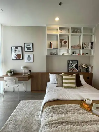Modern bedroom with stylish decor, built-in shelves, and cozy workspace.