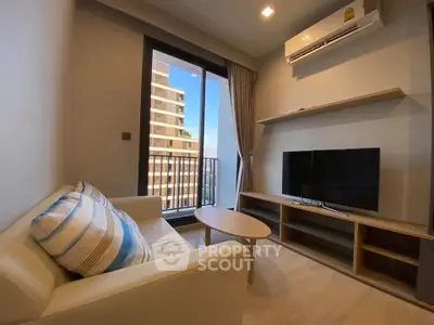 Modern living room with balcony view, featuring cozy sofa and sleek TV setup.