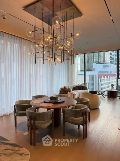 Luxurious living room with elegant chandelier and city view, featuring modern furniture and floor-to-ceiling windows.