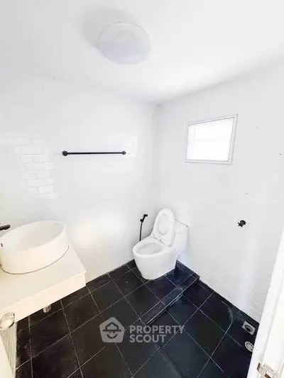 Minimalist white bathroom with black tile floor and modern fixtures.