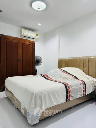 Cozy bedroom with air conditioning and stylish wooden wardrobe