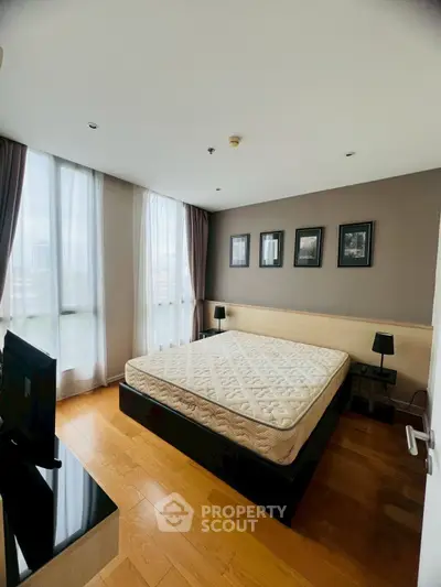 Spacious bedroom with large windows and modern decor in prime real estate location.