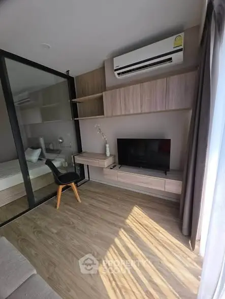 Modern living room with sleek design, featuring a TV, air conditioning, and stylish wooden flooring.
