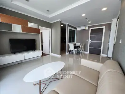 Modern living room with sleek furniture and open layout, featuring a stylish TV unit and elegant dining area.