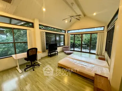 Spacious bedroom with large windows and balcony access, featuring modern furnishings and serene forest views.