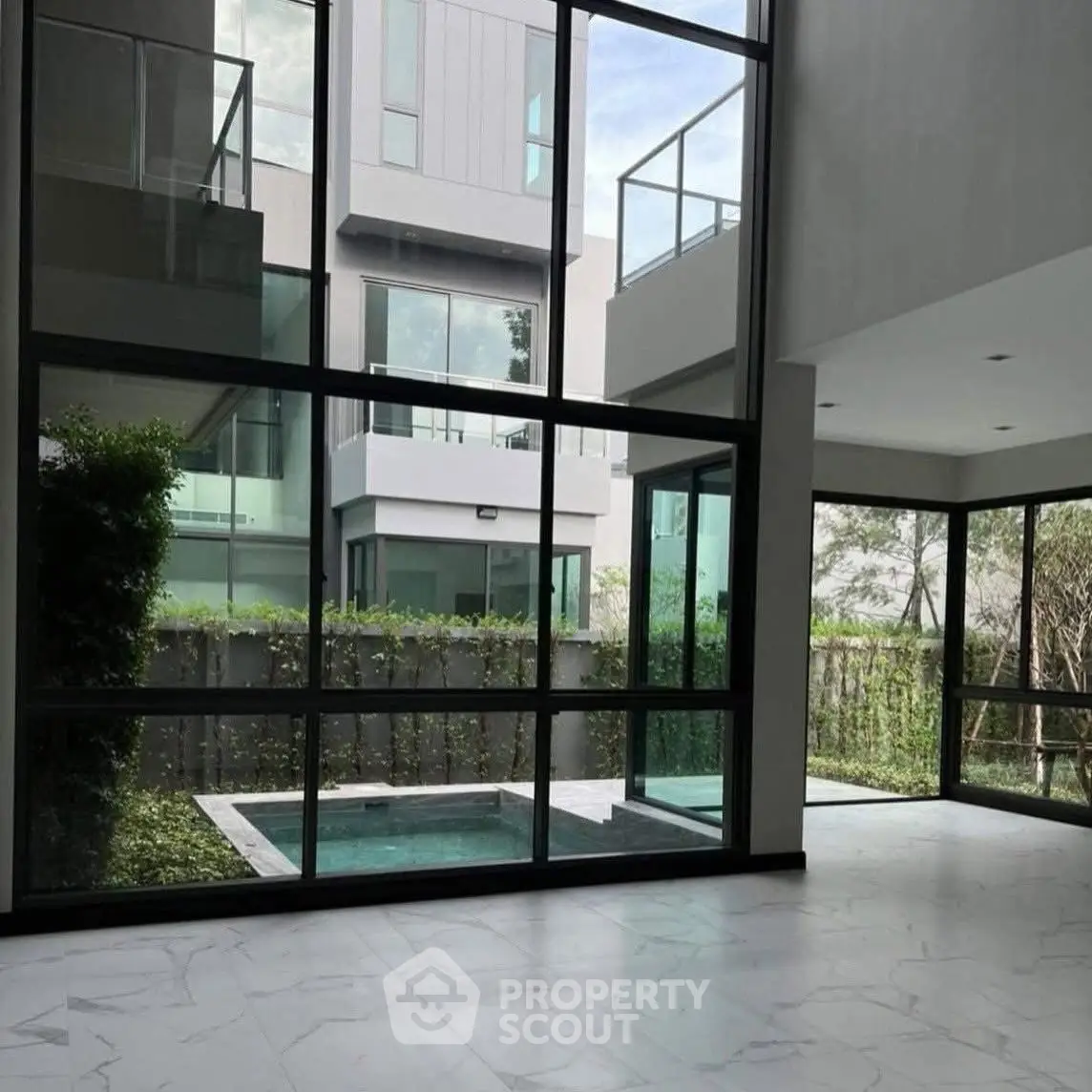Modern home interior with large windows overlooking a private pool and garden.
