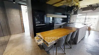 Modern kitchen with sleek design, featuring a wooden dining table and high-end appliances.