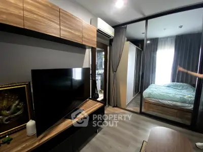 Modern apartment interior with sleek living room and cozy bedroom separated by glass partition.