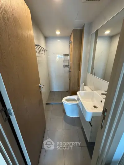 Modern bathroom with sleek fixtures and minimalist design, featuring a shower and elegant sink.