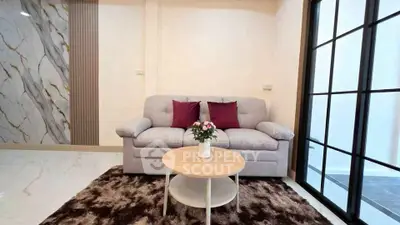 Stylish living room with cozy sofa, modern decor, and elegant marble accent wall.