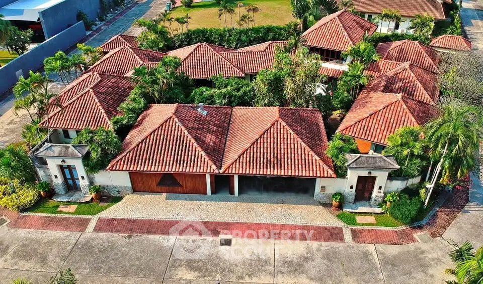 Luxurious villa with red-tiled roofs surrounded by lush greenery, showcasing exquisite architectural design.