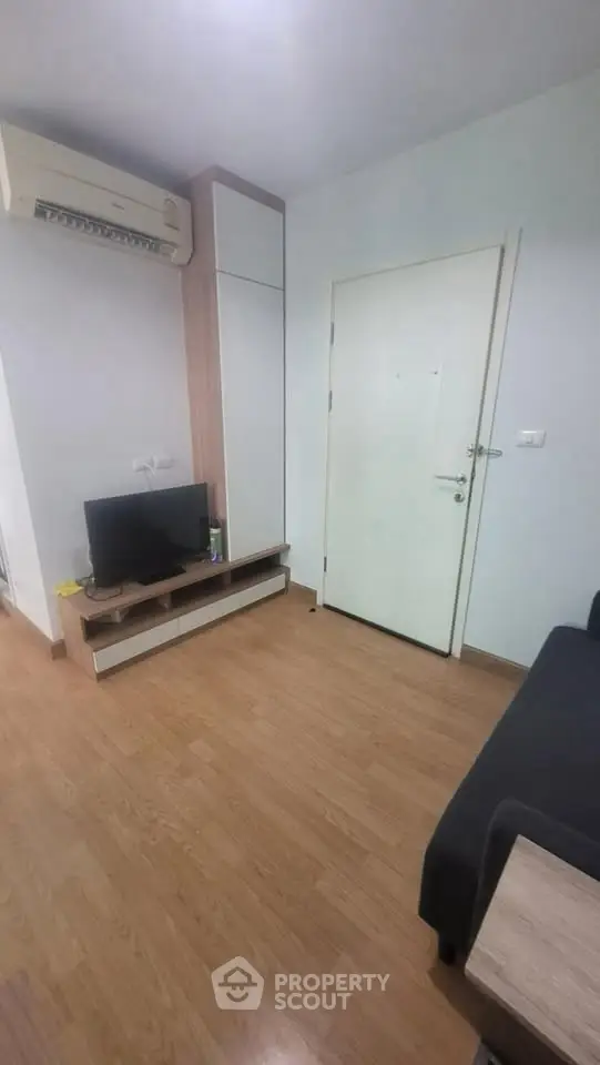 Modern living room with sleek wooden flooring and compact TV setup