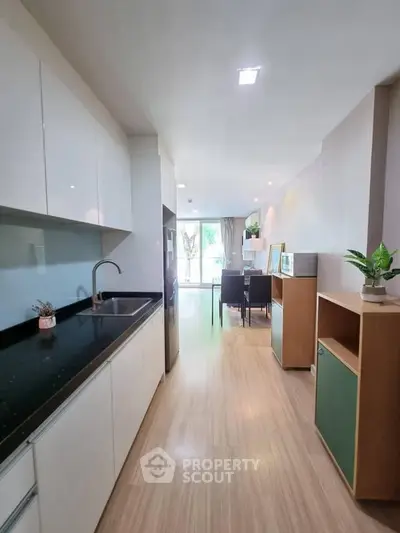 Modern open-layout kitchen with sleek cabinets and dining area, featuring natural light and stylish decor.