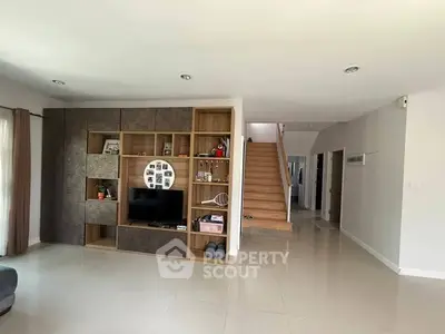 Spacious modern living room with stylish built-in entertainment center and elegant staircase.