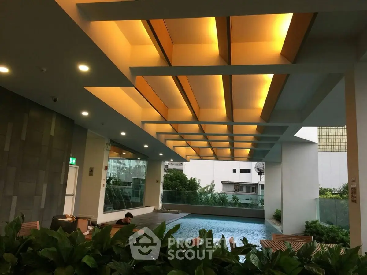 Luxurious modern pool area with stylish lighting and lush greenery in a high-end residential complex.