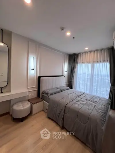 Modern bedroom with stylish decor and large window offering natural light.