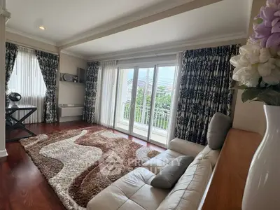 Elegant living room with plush rug and balcony view, featuring stylish curtains and cozy seating.