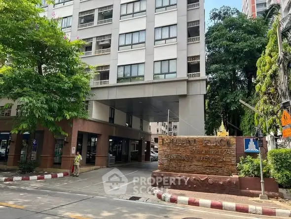 Modern apartment building entrance with lush greenery and clear signage.