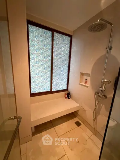 Modern bathroom with elegant shower and seating area, featuring stylish frosted window design.