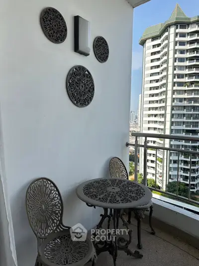 Charming balcony with decorative metal furniture and city view in modern high-rise apartment.