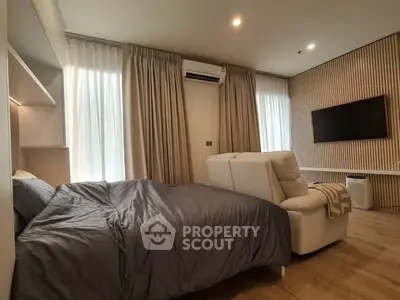 Modern bedroom with cozy bed, stylish recliner, and wall-mounted TV, perfect for relaxation.