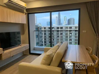 Modern living room with large windows offering a city view, sleek furnishings, and a cozy ambiance perfect for urban living.