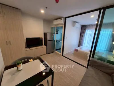 Modern studio apartment with open layout, featuring a cozy living area, compact kitchen, and glass-walled bedroom.