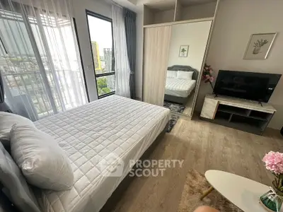 Modern bedroom with large window, stylish decor, and natural light in urban apartment.
