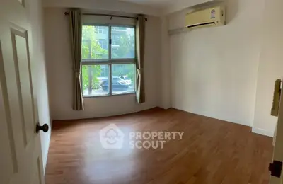 Spacious empty room with wooden flooring and large window, perfect for customization.