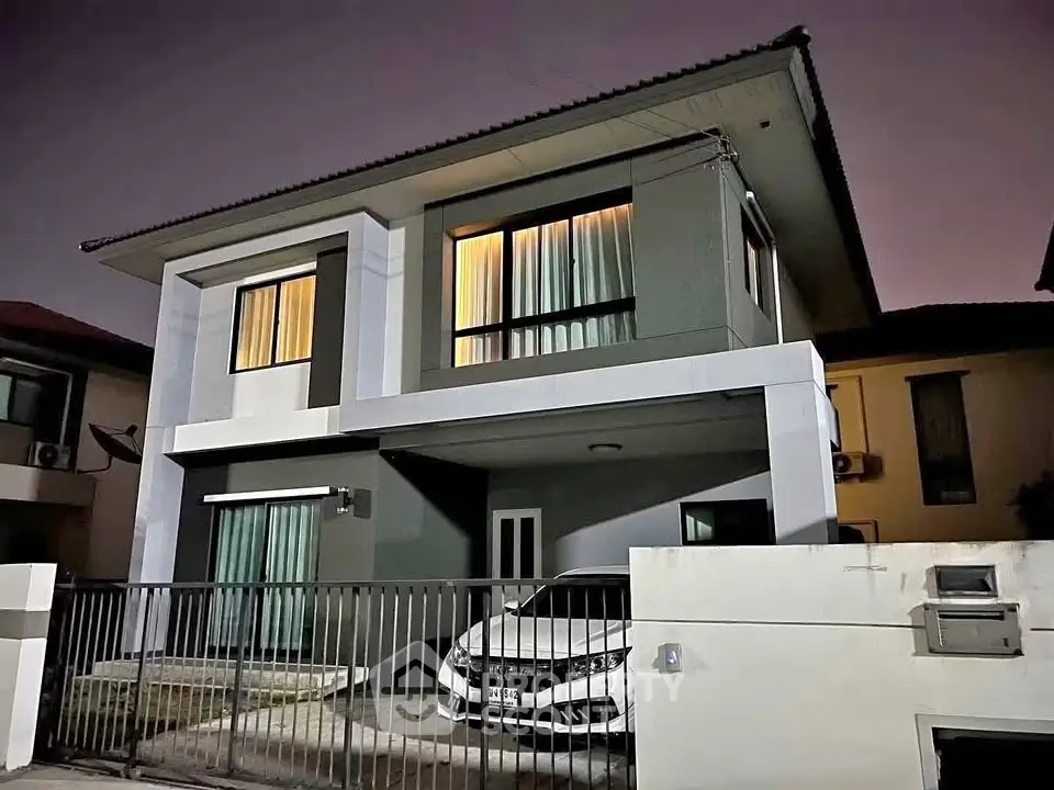 Modern two-story house with sleek design and car parked in driveway at dusk.