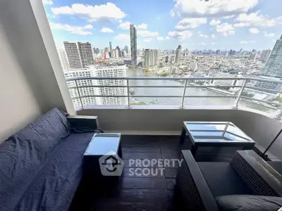 Stunning high-rise balcony with panoramic city and river views, featuring cozy outdoor seating.